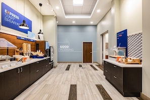 A modern hotel lobby with a breakfast bar, a 'Good Morning' sign, and a 'This is how we roll' sign.