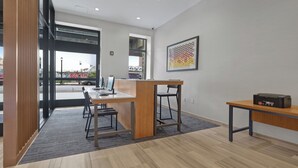 A modern office space with a desk, computer, and printer. There is a window with a view of the street and graffiti. - Hotel 1200 (Brooklyn)
