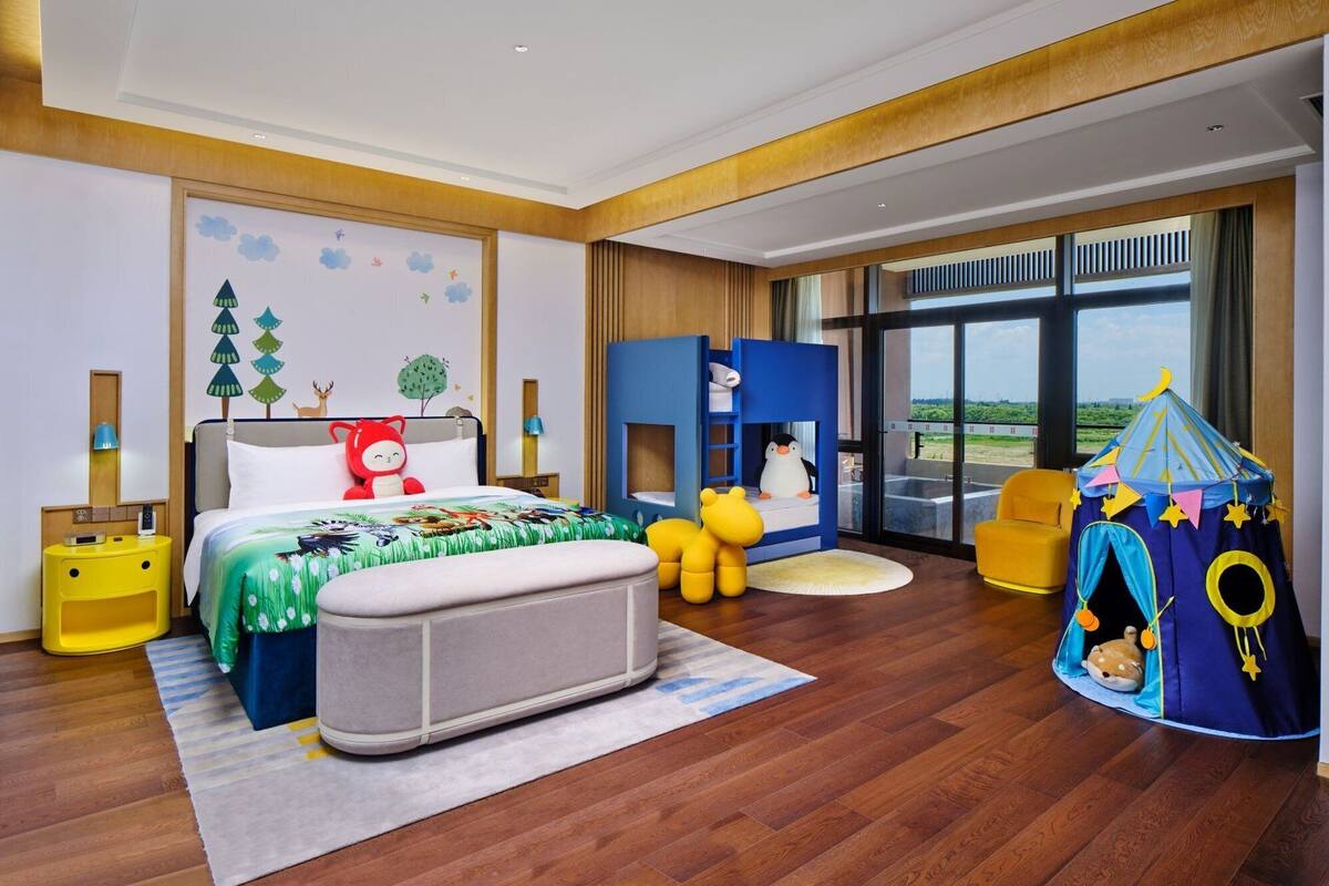 A modern hotel room with a large bed, a play area, and a view of the outdoors.