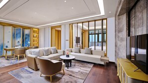 A modern hotel room with a sofa set, a coffee table, a TV, and a desk with a chair. - HUALUXE Suzhou Bay Hot Spring Resort by IHG (Suzhou)