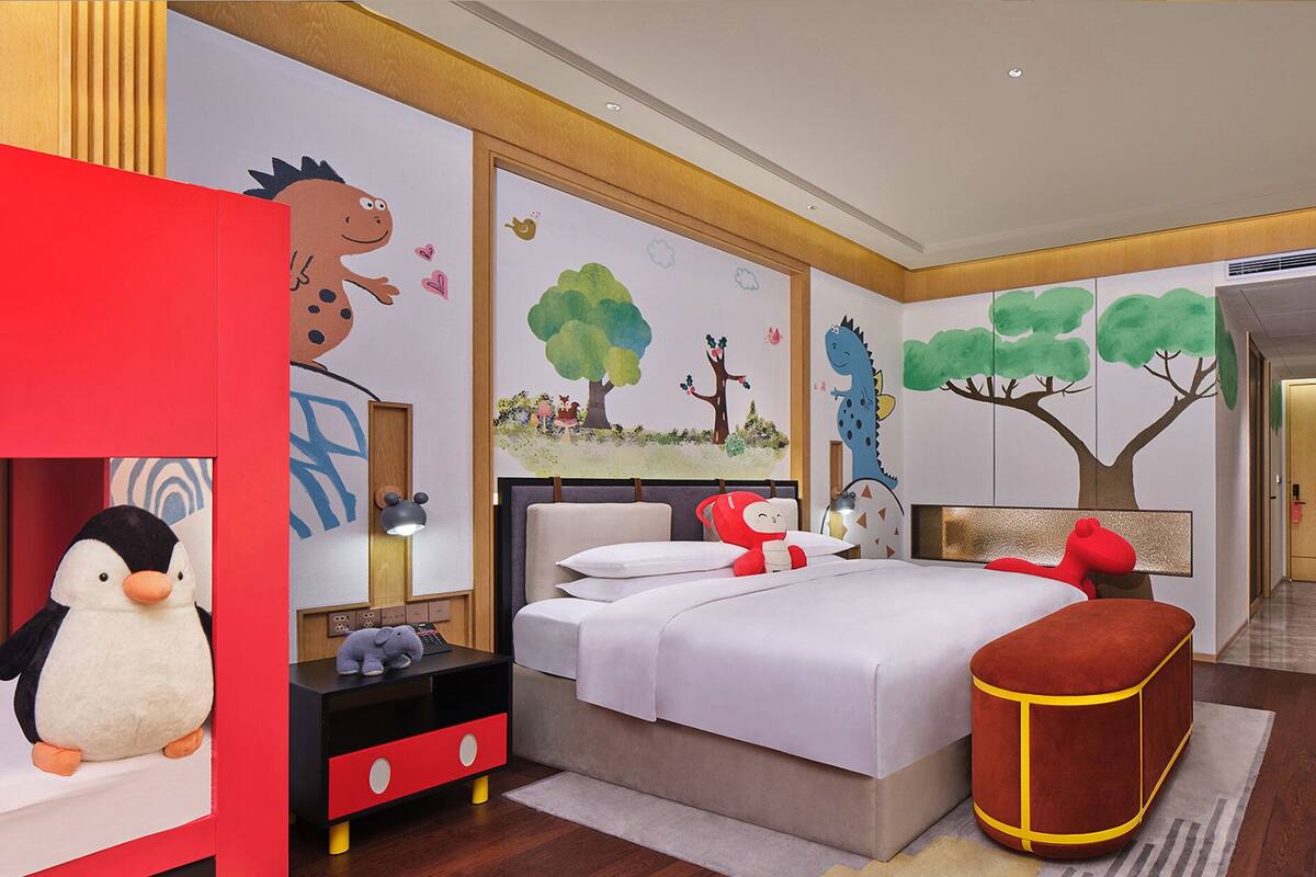 A child's bedroom with a bed, nightstand, dresser, and plush toys.