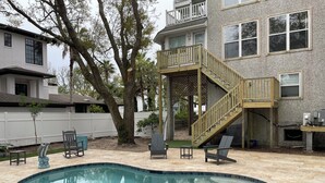 A backyard with a swimming pool, a wooden deck, and a white fence. - Steps from the beach with private pool Oceanview Home rooftop view 5BR Sleep 15 (St. Simons Island)
