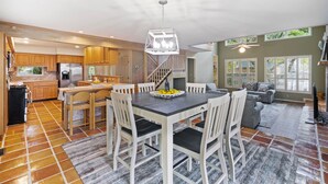 A spacious kitchen with wooden cabinets, a dining area with a table and chairs, and a living room with a sofa and a TV. - Steps from the beach with private pool Oceanview Home rooftop view 5BR Sleep 15 (St. Simons Island)