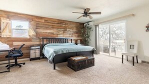 A bedroom with a wooden wall, a bed, a desk, a chair, a suitcase, and a ceiling fan. - Explore natures retreat with amazing views of Lake Tulloch and close to Yosemite (Copperopolis)