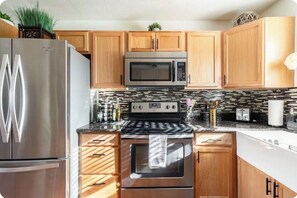 A modern kitchen with stainless steel appliances, wooden cabinets, and a tiled backsplash. - Explore natures retreat with amazing views of Lake Tulloch and close to Yosemite (Copperopolis)