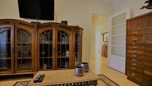 A living room with a wooden cabinet, a television mounted on the wall, and a table with two decorative vases.