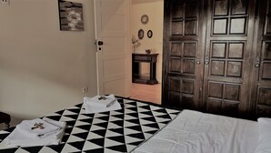 A room with a black and white checkered floor, a bed with white bedding, and a wooden door with a panel design.