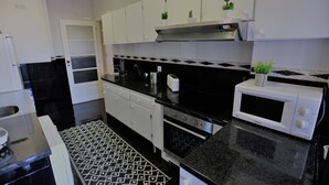 A modern kitchen with white cabinets, black countertops, a patterned floor, and a microwave.