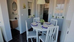 A dining area with a round table set for four, white chairs, and a hanging light fixture.