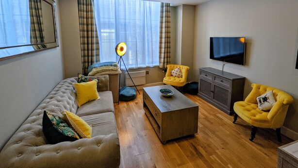 Ett modernt vardagsrum med en soffa, fåtöljer, ett soffbord och en platt-TV.