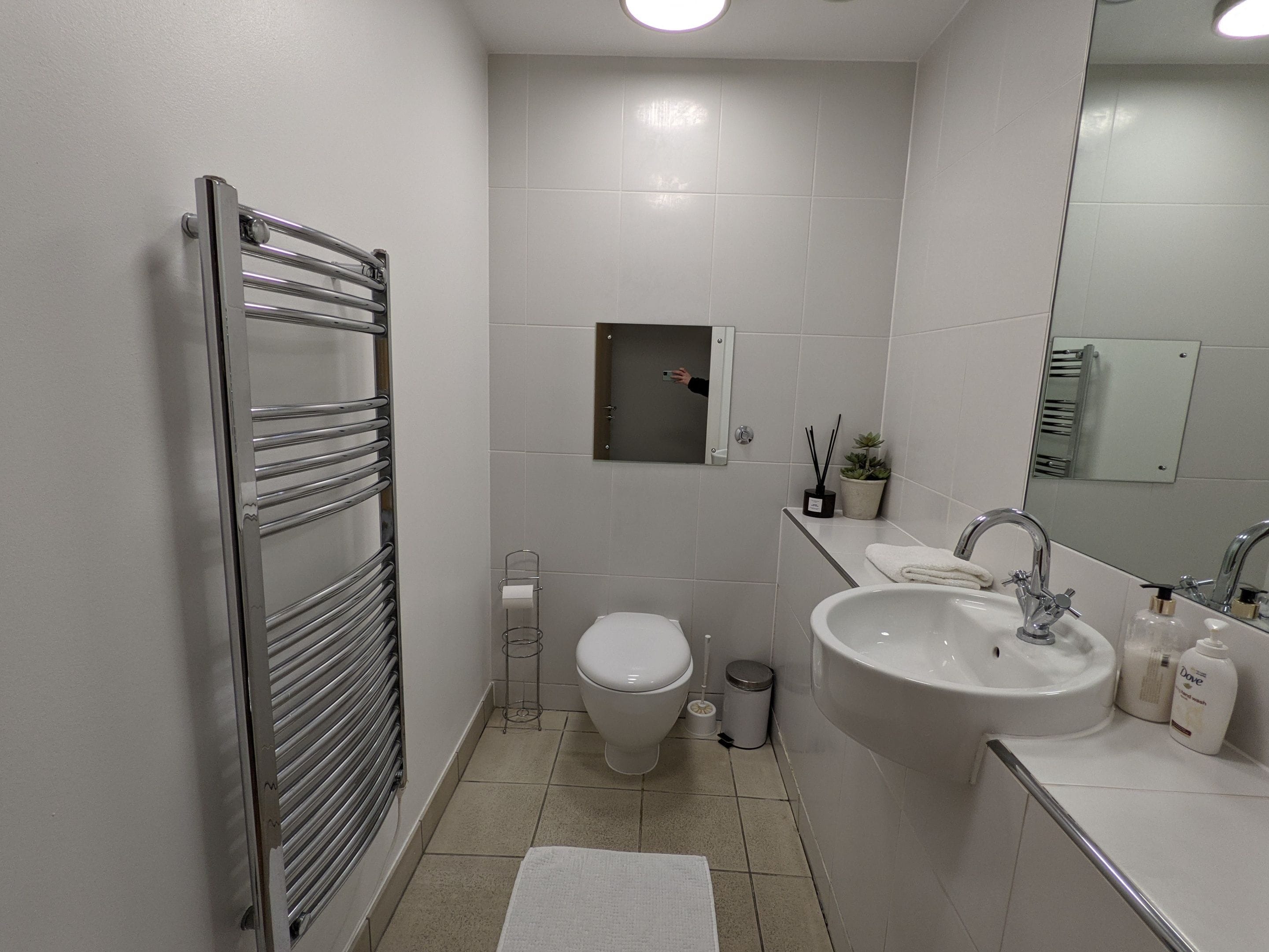 Een moderne badkamer met toilet, wastafel en handdoekhouder.