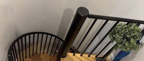 A spiral staircase with wooden steps and black metal railings.