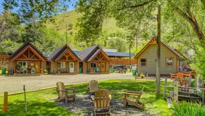 A rustic lodge with multiple cabins, outdoor seating, and a gravel driveway.