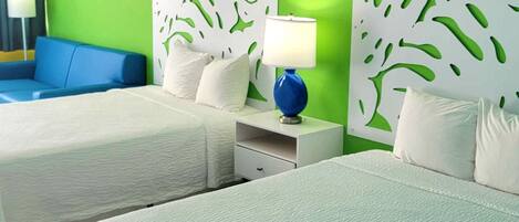 Une chambre d’hôtel avec deux lits, un canapé bleu et un mur d’accent vert.