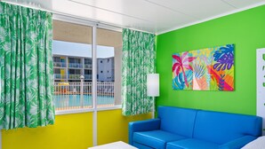 Um quarto com uma parede verde vibrante, um sofá azul, uma mesa branca e uma janela com cortinas verdes.