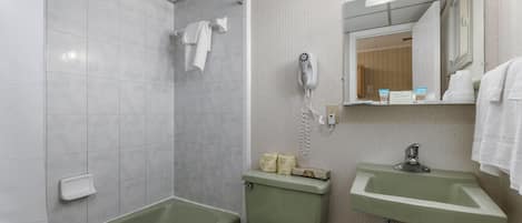 A bathroom with a green bathtub, a white toilet, a sink, and a hairdryer on the wall.