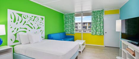 A hotel room with a bed, a blue sofa, a TV, and a window with curtains.