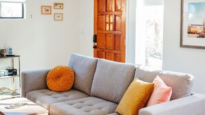Una sala de estar con un sofá seccional, una mesa de centro de madera y un tapete estampado.