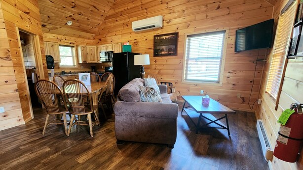 Interior de una cabaña de madera con comedor, sofá y cocina.