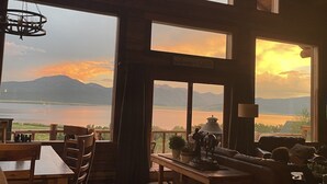 A cabin with large windows offering a view of a lake and mountains. - NO BETTER VIEW THAN THIS (Island Park)