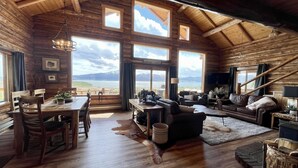 A cabin with a wooden interior, large windows, a dining area, and a cozy living space with a fireplace. - NO BETTER VIEW THAN THIS (Island Park)