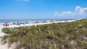 Une plage avec des gens, des parasols et des chaises de plage.