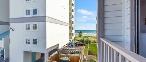 Un immeuble à plusieurs étages doté de balcons donnant sur une plage.
