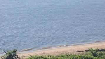 A beach with calm waters and a distant boat.