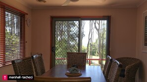 Enjoy meals in this dining area with a table and four chairs, surrounded by a view of trees and a lawn.