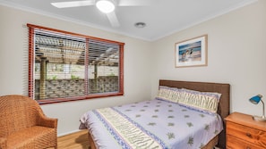A bedroom with a bed, a chair, a nightstand, a lamp, and a painting on the wall.
