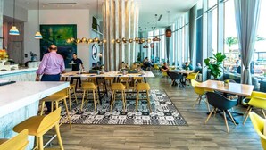 Un restaurante moderno con techos altos, ventanas amplias y un suelo con diseño en amarillo y negro.