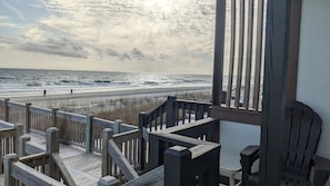 Eine Holzterrasse mit Blick auf Strand und Meer.