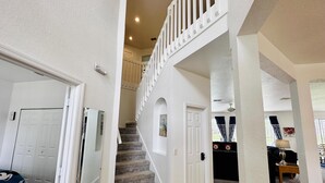 A multi-level home interior with a staircase, white walls, and a tiled floor. - Modern and Well Equipped 6/3 Pool Home on Golf Community. Perfectly accommodating for families with ample space inside and out! (Davenport)