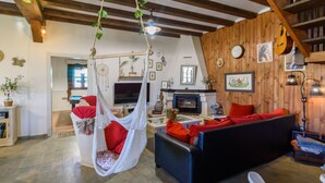 A cozy living room with a hanging chair, a sofa, and a fireplace. - Finca El Albero Carratraca by Ruralidays (Málaga)