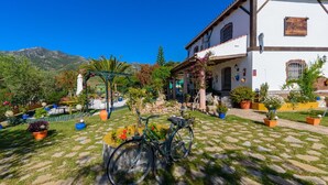 A courtyard with a bicycle, potted plants, and a building with a sign reading "Finca El Alamo". - Finca El Albero Carratraca by Ruralidays (Málaga)