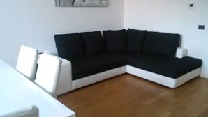 Una sala de estar moderna con un sofá modular blanco y negro, una mesa de centro blanca y un cuadro en la pared.