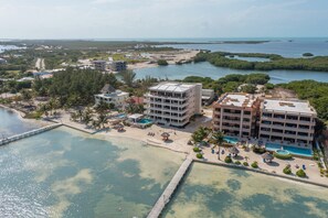 Ein Küstenhotel mit mehreren Gebäuden, einem Strand und einem Steg.