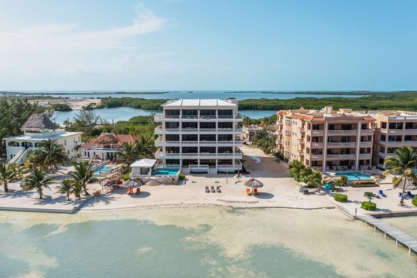 A resort with multiple buildings, a swimming pool, and a beach area. - Ocean’s Edge 4A – Fourth-Floor Beachfront Condo with Sweeping Caribbean Views (Ambergris Caye)