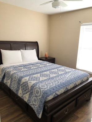 A bedroom with a bed, a nightstand, a heater, and a window. - Villa dos Palmas (Cape Coral)