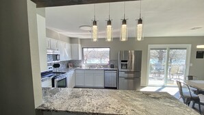 A modern kitchen with granite countertops, stainless steel appliances, and pendant lighting. - Waterfront house with private dock and boat slip (Stigler)