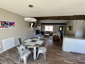 A spacious living area with a dining table, chairs, a sofa, and a kitchen area with a countertop and cabinets. - Waterfront house with private dock and boat slip (Stigler)