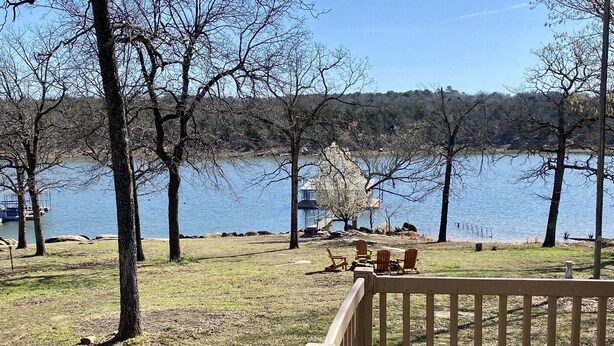 A lakeside view with a wooden deck, chairs, and a gazebo. - Waterfront house with private dock and boat slip (Stigler)