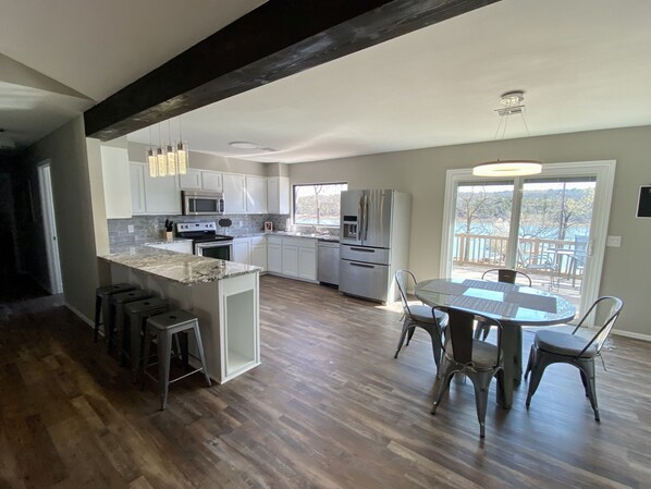 A spacious kitchen with a central island, stainless steel appliances, and a dining area with a view. - Waterfront house with private dock and boat slip (Stigler)