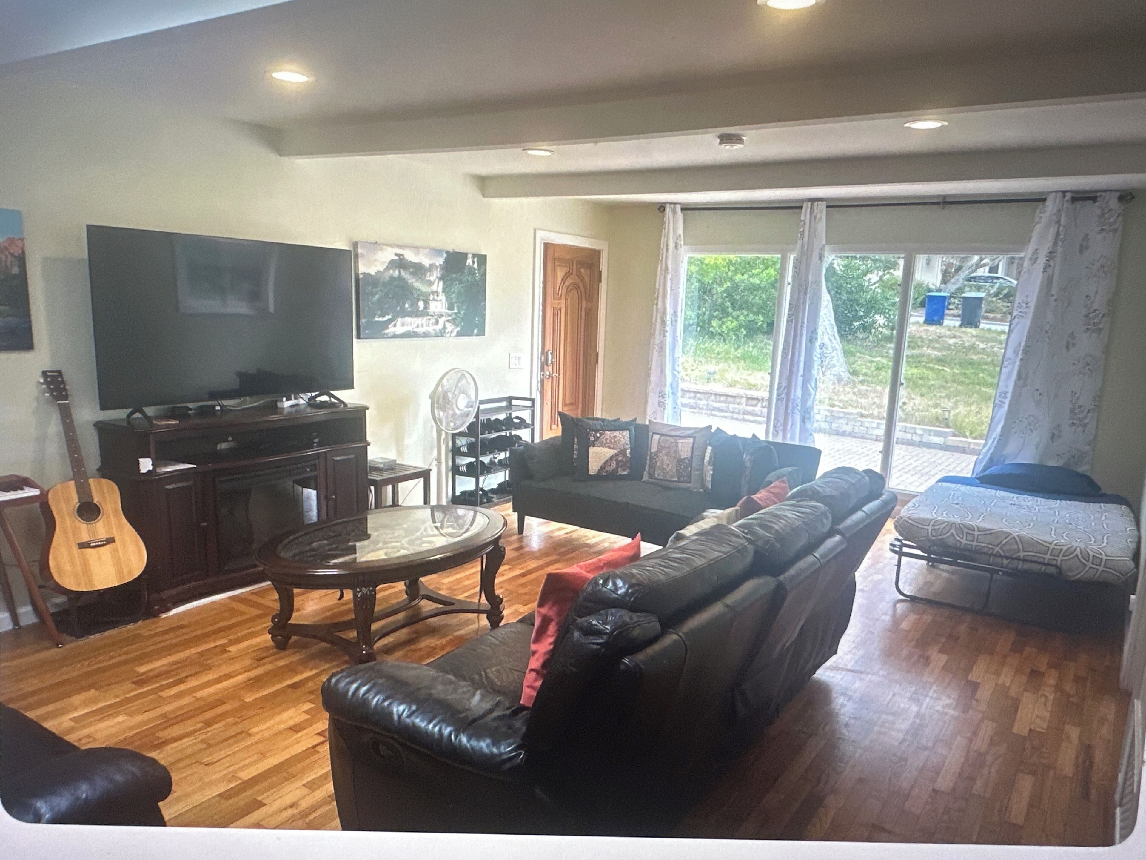 A living room with a television, a guitar, a sofa, and a coffee table.