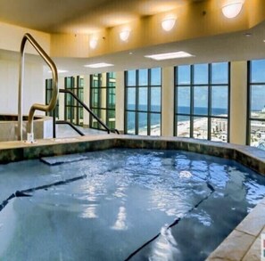 Swim laps in the pool surrounded by ocean views through large windows.