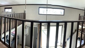 Une chambre spacieuse et bien éclairée, située dans les combles, avec un escalier en colimaçon, de grandes fenêtres et un coin salon confortable.