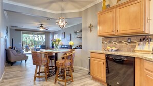 A modern kitchen with wooden cabinets, a dishwasher, and a dining area with a round table and chairs.