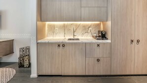 A modern kitchen with light wood cabinetry, a marble countertop, and a built-in sink. - ★LUXURIOUS★ King Suite Located at SLS Lux Brickell Building (Miami)