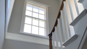A staircase with white railings and a wooden handrail, leading to a room with a window. - Elegant 2 Bed Georgian Apartment in Herne Bay (Herne Bay)