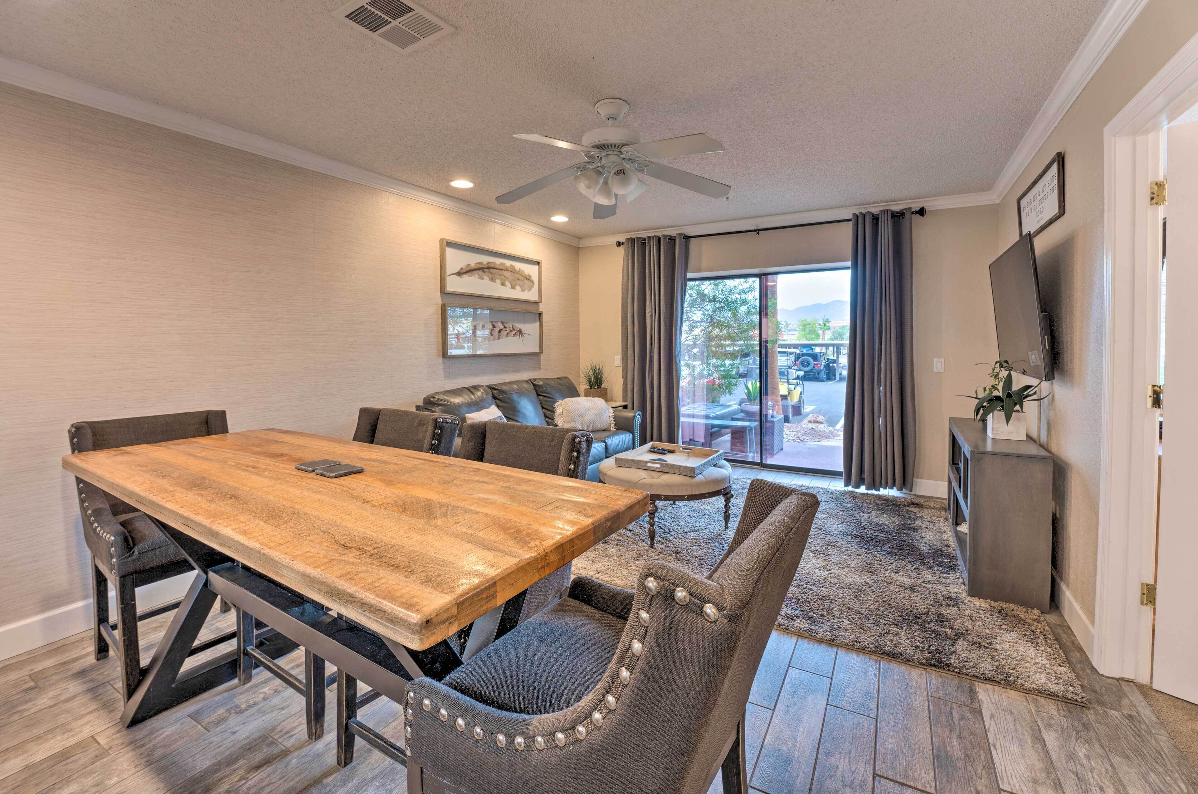 A dining area with a wooden table and metal chairs, a ceiling fan, and a view through a glass door to the outdoors.